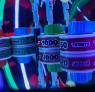 Stacks of tickets are arranged on a reflective surface, featuring various numerical values. Vibrant neon lights in red, blue, and green create a lively, arcade-like atmosphere, casting colorful reflections.